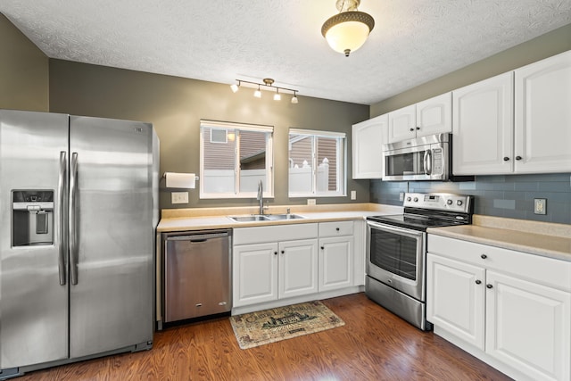 kitchen with dark wood-style flooring, appliances with stainless steel finishes, white cabinetry, and a sink