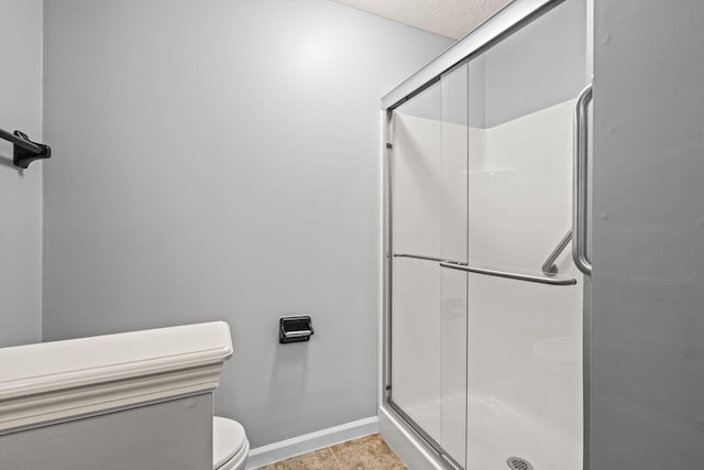 full bathroom with baseboards, toilet, and a shower stall