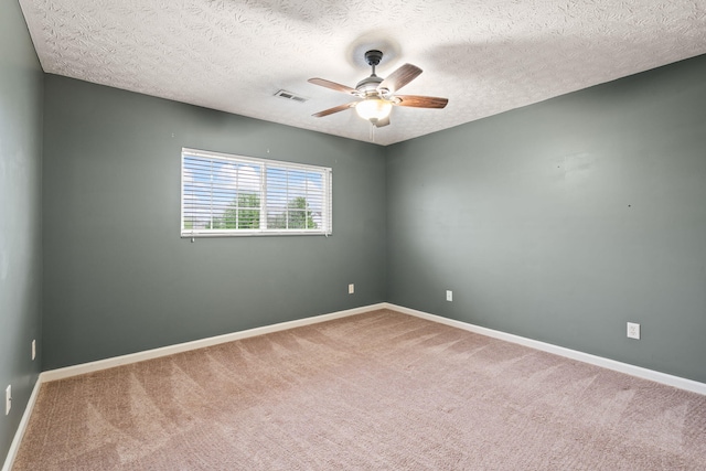 carpeted empty room with baseboards, ceiling fan, a textured ceiling, and visible vents