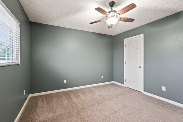 carpeted spare room featuring a ceiling fan, a textured ceiling, and baseboards