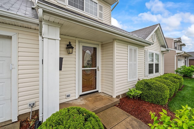 entrance to property featuring roof with shingles