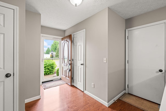 entryway with baseboards, a textured ceiling, and wood finished floors