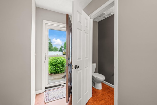 bathroom with baseboards, toilet, and wood finished floors