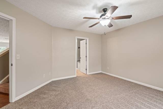 empty room featuring baseboards, a ceiling fan, a textured ceiling, and light carpet