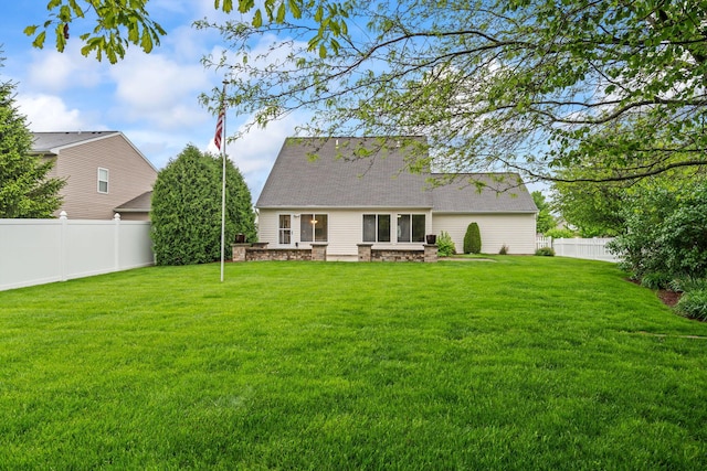 rear view of property with a lawn, a fenced backyard, and roof with shingles