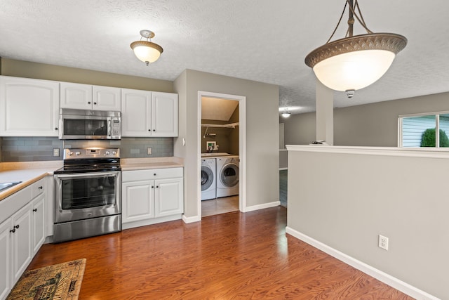 kitchen with washing machine and clothes dryer, light countertops, a textured ceiling, stainless steel appliances, and backsplash