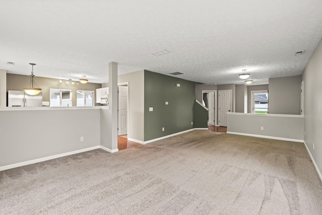 unfurnished living room featuring baseboards, carpet flooring, a textured ceiling, and visible vents