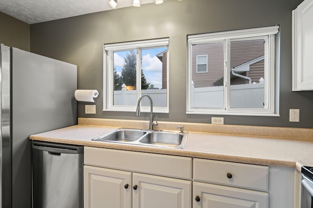 kitchen with light countertops, a sink, white cabinets, and stainless steel appliances