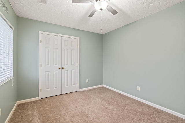 unfurnished bedroom featuring carpet flooring, a textured ceiling, baseboards, and a closet