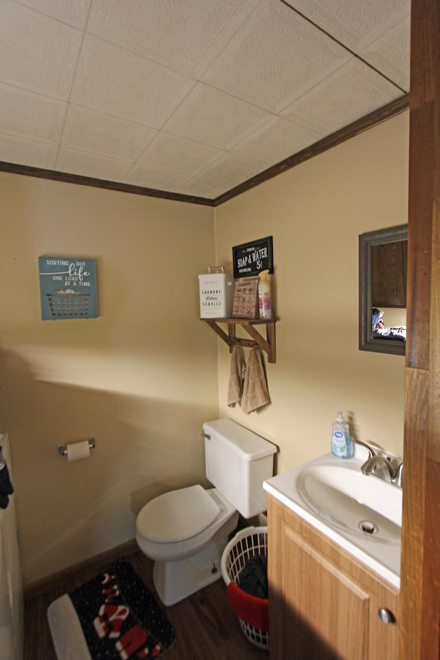 half bathroom with toilet, crown molding, wood finished floors, and vanity