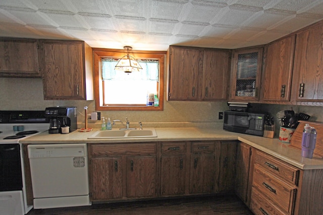 kitchen with light countertops, white appliances, a sink, and glass insert cabinets