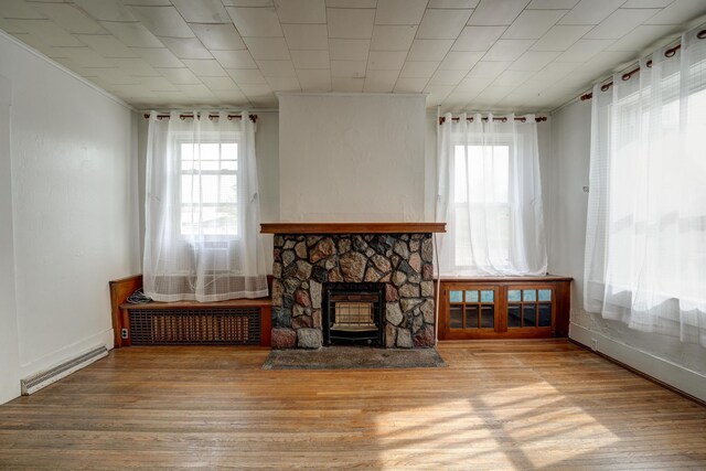 living room with baseboards, a stone fireplace, wood finished floors, and visible vents