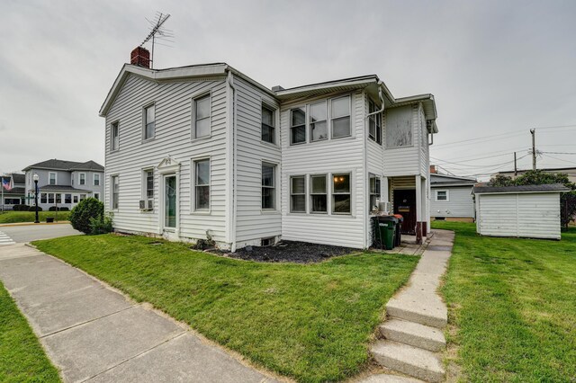 view of front of house featuring an outdoor structure, a front lawn, and a chimney