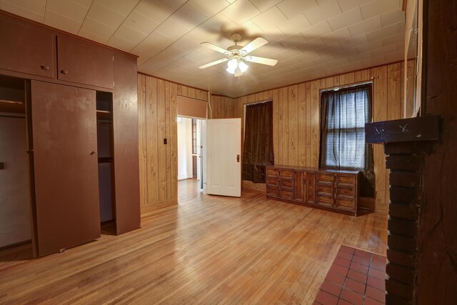 unfurnished bedroom featuring light wood-style floors, wood walls, and a closet