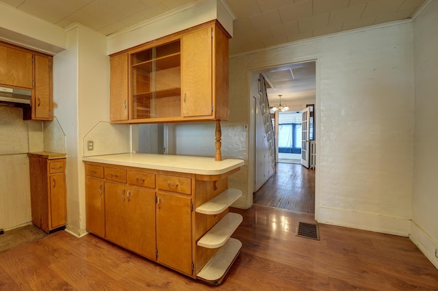 kitchen featuring crown molding, open shelves, light wood finished floors, light countertops, and under cabinet range hood