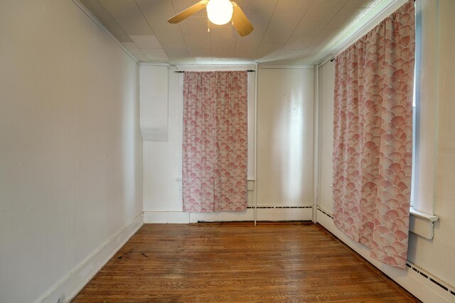 spare room with ceiling fan, a baseboard heating unit, and wood finished floors