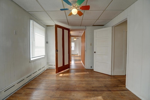unfurnished room with wood-type flooring, a ceiling fan, and a baseboard radiator
