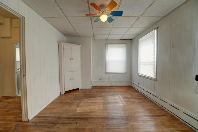 49 S W St, Versailles, OH 45380 - empty room featuring hardwood / wood-style flooring, a baseboard heating unit, a baseboard radiator, a drop ceiling, and a ceiling fan