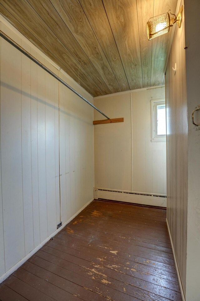interior space with wood ceiling, wood walls, baseboard heating, and hardwood / wood-style floors