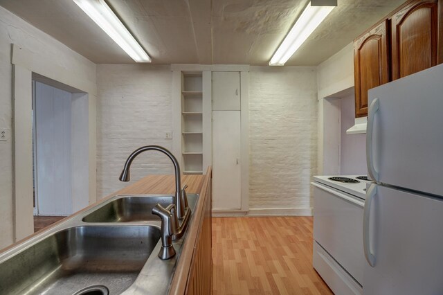 kitchen with brown cabinets, a sink, light wood-style floors, white appliances, and under cabinet range hood