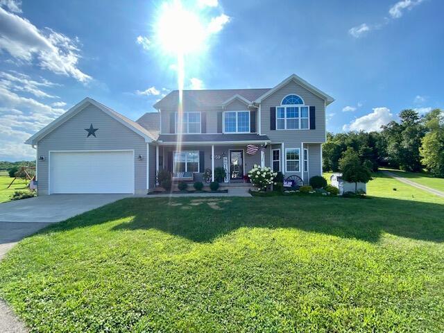 view of front facade with a porch, a garage, concrete driveway, and a front yard