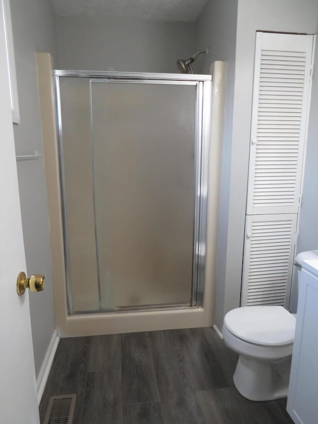 full bath with toilet, baseboards, a shower stall, wood finished floors, and visible vents