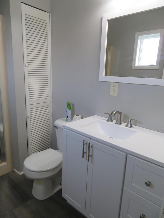 full bath featuring vanity, walk in shower, wood finished floors, and toilet