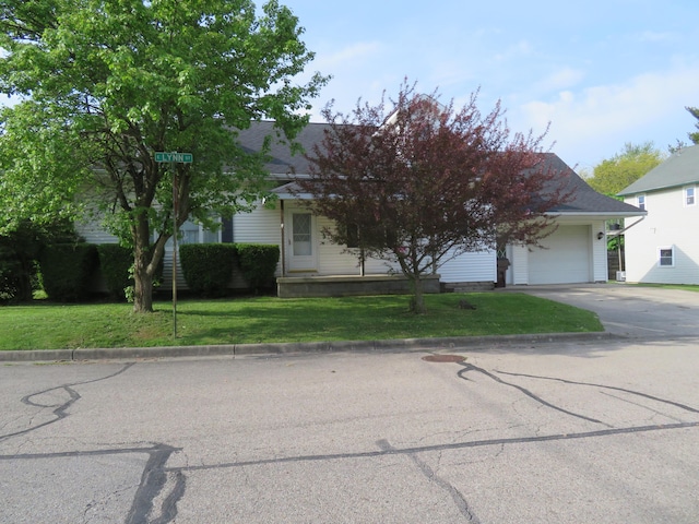 obstructed view of property featuring concrete driveway, an attached garage, and a front lawn