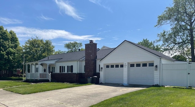 view of front of house featuring concrete driveway, a front yard, a chimney, and an attached garage