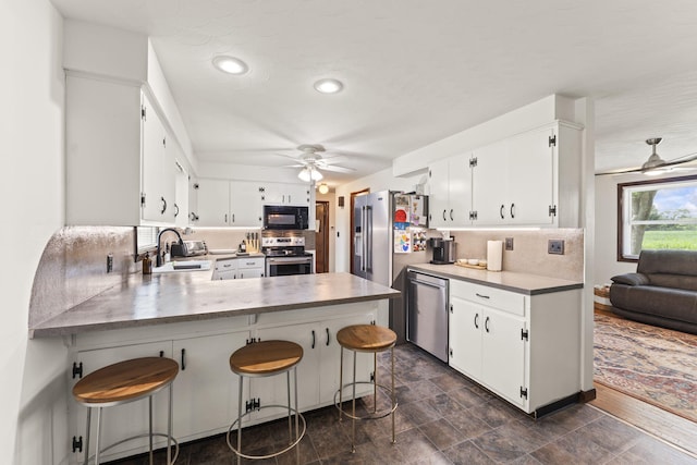 5899 N Springcreek Stringtown Rd, Piqua, OH 45356 - kitchen with stainless steel appliances, a ceiling fan, backsplash, a peninsula, and white cabinetry
