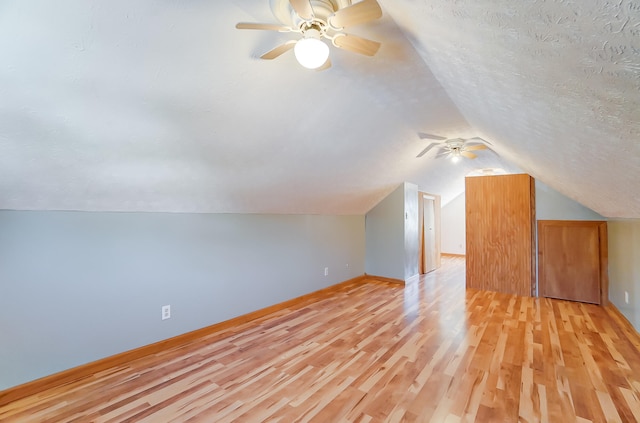 additional living space with vaulted ceiling, ceiling fan, a textured ceiling, and light hardwood / wood-style floors