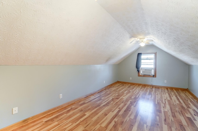 bonus room featuring cooling unit, vaulted ceiling, light hardwood / wood-style flooring, and a textured ceiling