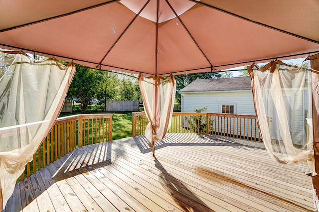 wooden terrace with a gazebo and a lawn