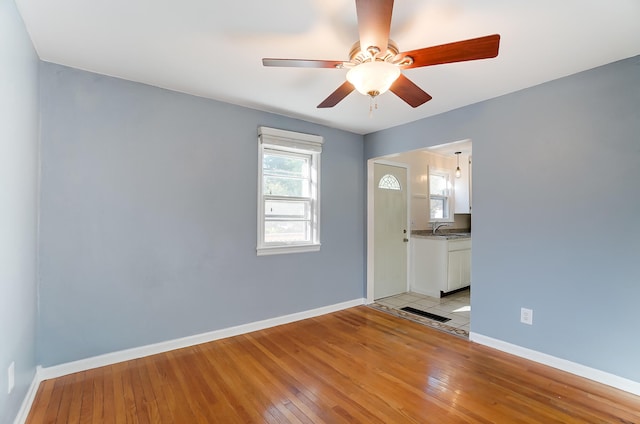 unfurnished room with ceiling fan, sink, and light wood-type flooring