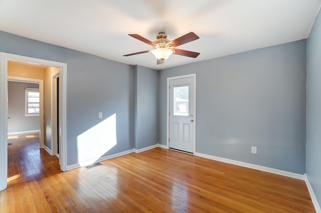 empty room with ceiling fan, a healthy amount of sunlight, and light hardwood / wood-style floors