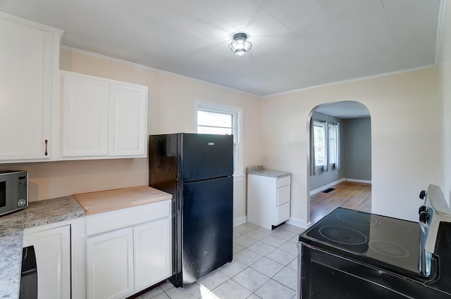 kitchen featuring ornamental molding, light tile patterned floors, white cabinets, and black appliances