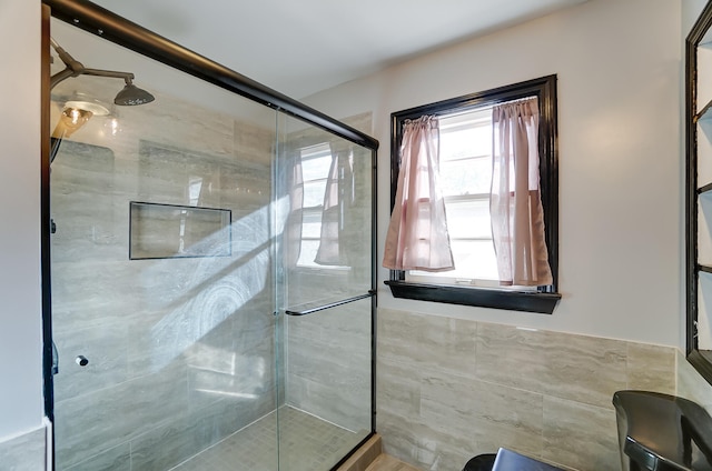 bathroom with tile walls and a shower with shower door