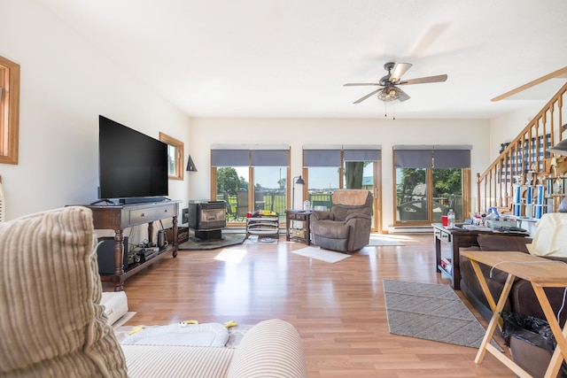 13730 Seminole Path, Lakeview, OH 43331 - living room with stairs, a wood stove, ceiling fan, and light wood-style floors