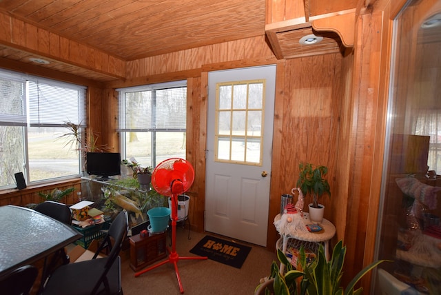 doorway to outside featuring wooden ceiling, carpet floors, and wood walls