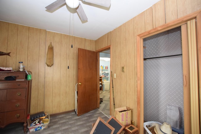 bedroom featuring light carpet, ceiling fan, and wood walls