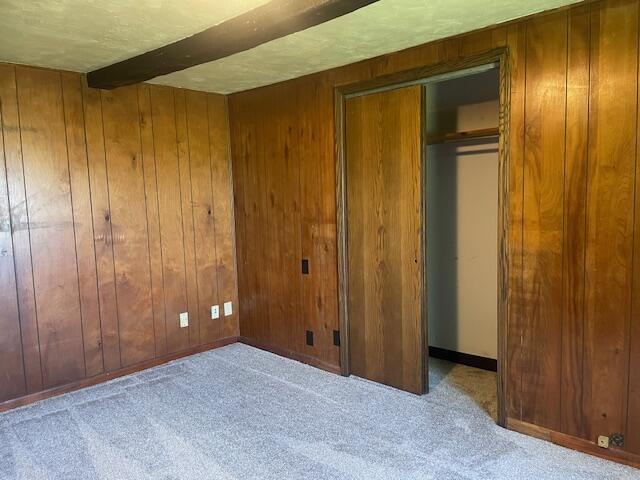 9770 Agerter Rd, Spencerville, OH 45887 - unfurnished bedroom with carpet, wooden walls, beamed ceiling, and a closet
