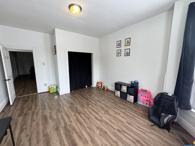 bedroom with visible vents, a textured ceiling, and wood finished floors