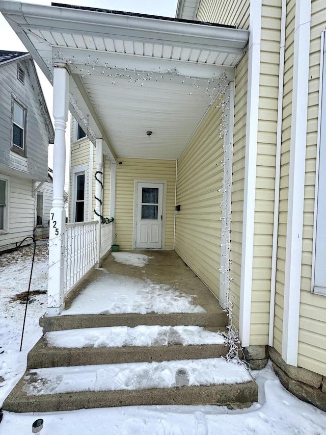 snow covered property entrance featuring an attached carport