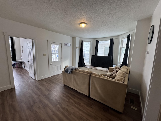 living area featuring a textured ceiling, dark wood finished floors, and baseboards