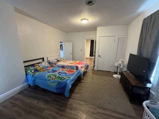 bedroom featuring visible vents, a closet, baseboards, and dark wood-type flooring