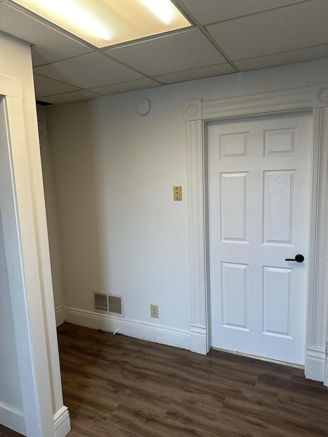 unfurnished room with dark wood-style floors, baseboards, visible vents, and a drop ceiling