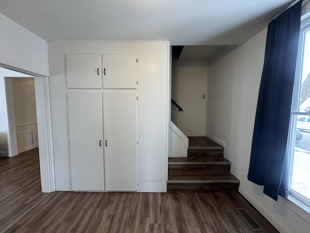 stairway with a healthy amount of sunlight, visible vents, baseboards, and wood finished floors