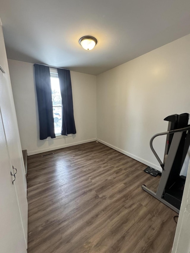 interior space featuring dark wood-type flooring, visible vents, and baseboards