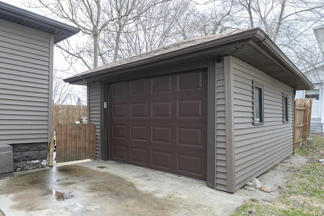 detached garage featuring fence and concrete driveway