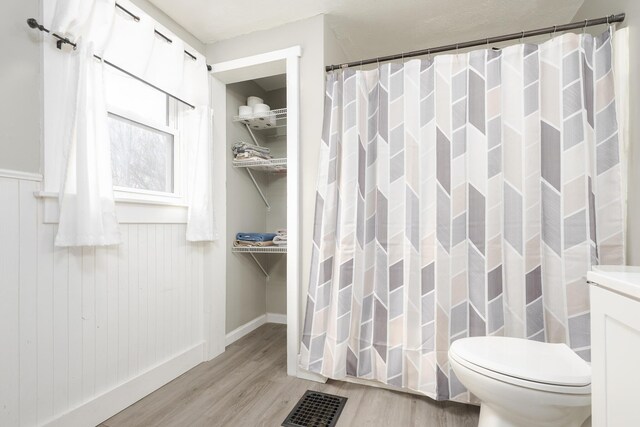 bathroom with visible vents, wood finished floors, toilet, and a shower with shower curtain